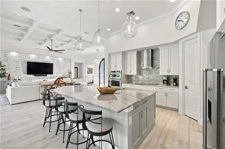 Kitchen featuring a large center island with stone countertops, white cabinetry, a coffered ceiling, wood-finish tile flooring, and glass pendant lighting