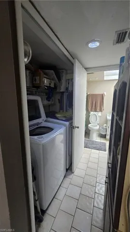 Washroom featuring light tile patterned floors and washing machine and clothes dryer