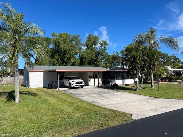 View of parking with a lawn and a carport