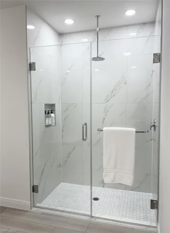 Glass-enclosed shower with large format tile walls and a hexagonal tile floor