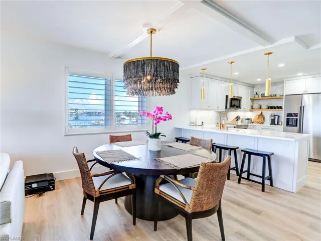 Dining room with sink, light wood-type flooring, and an inviting chandelier