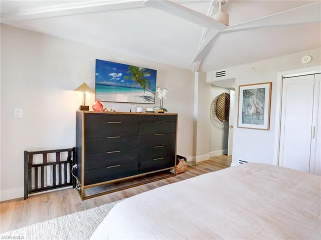 Bedroom featuring light hardwood / wood-style flooring, lofted ceiling with beams, and ceiling fan