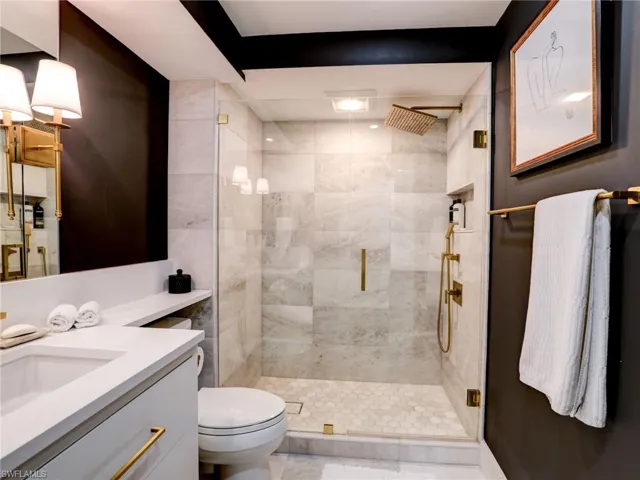 Bathroom featuring vanity, walk in shower, and toilet