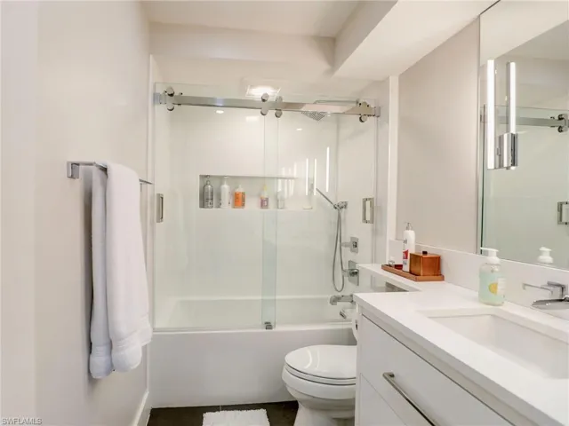 Full bathroom featuring vanity, toilet, and combined bath / shower with glass door