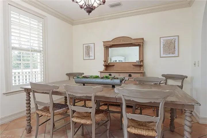 Dining room with crown molding, light tile patterned flooring, and a chandelier