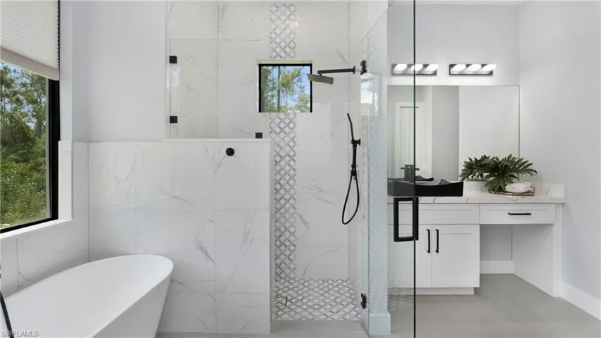 Bathroom with a marble finish shower, a freestanding tub, and vanity