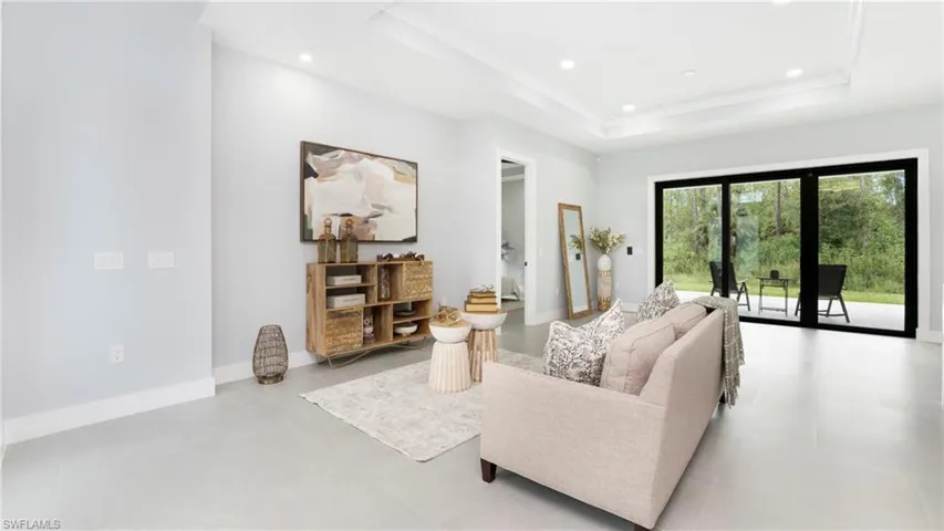 Living room with recessed lighting, a raised ceiling, and ornamental molding