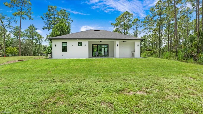 Rear view of house with a patio, a lawn, stucco siding, a ceiling fan, and a shingled roof