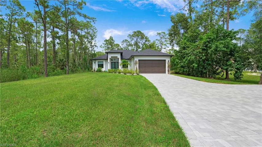 View of front of property with a garage, a front lawn, decorative driveway, and stucco siding