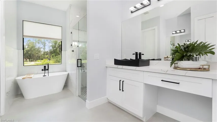 Bathroom featuring vanity, a stall shower, a freestanding tub, tile walls, and light tile patterned floors