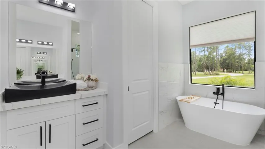 Full bathroom with vanity, a freestanding bath, light tile patterned floors, and tile walls