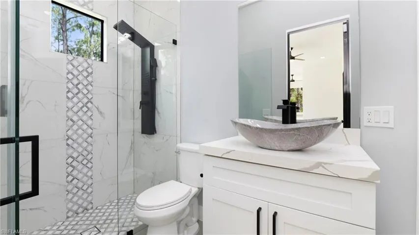 Full bath with plenty of natural light, a marble finish shower, and vanity