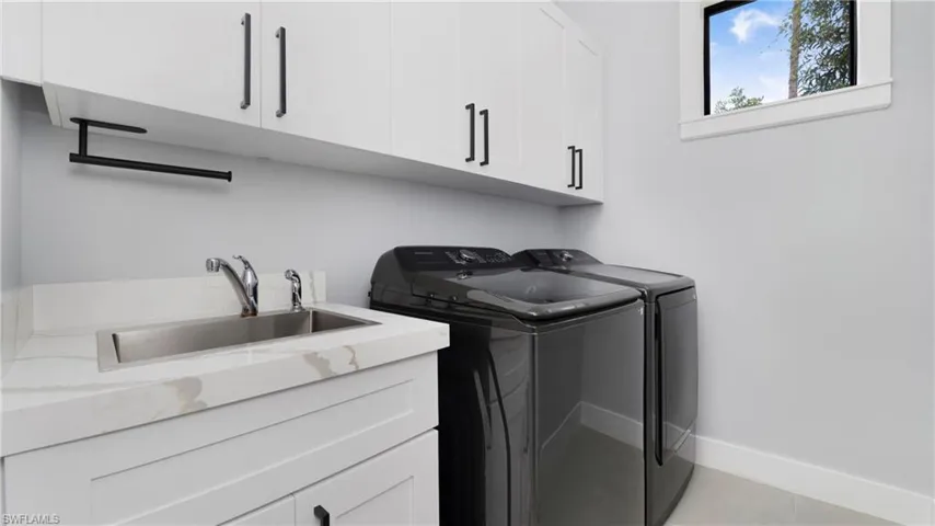Laundry room featuring cabinet space, light tile patterned flooring, and separate washer and dryer