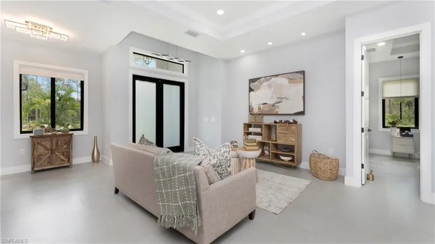 Living room featuring natural light, a raised ceiling, recessed lighting, and crown molding