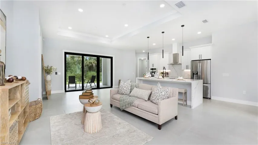 Living area featuring a raised ceiling, recessed lighting, and crown molding