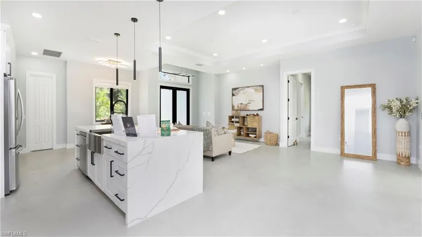 Kitchen with white cabinets, light stone countertops, open floor plan, freestanding refrigerator, and recessed lighting