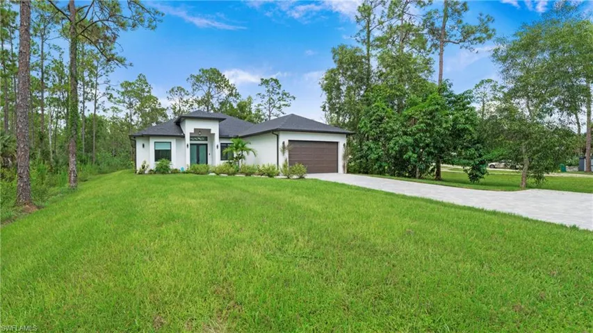 View of front of house featuring decorative driveway, a front lawn, stucco siding, and an attached garage