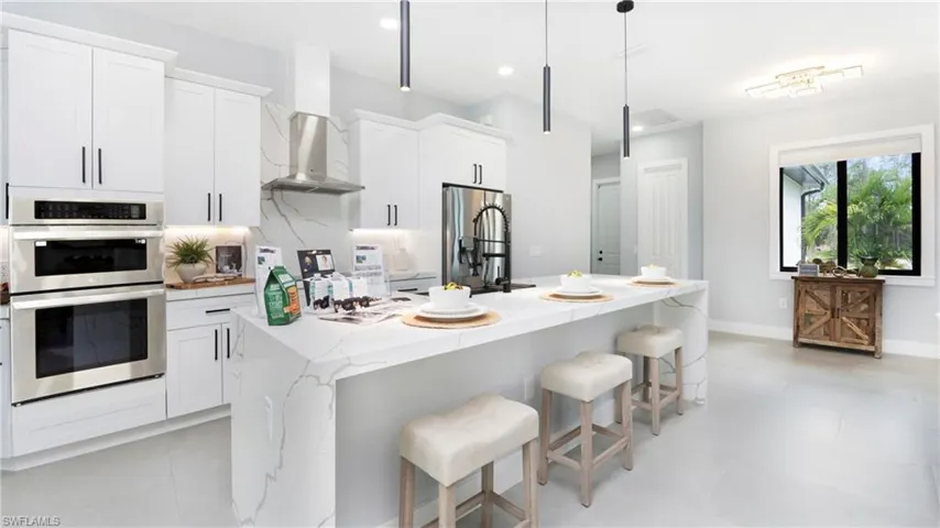 Kitchen featuring white cabinetry, light stone counters, stainless steel appliances, a kitchen island with sink, and recessed lighting