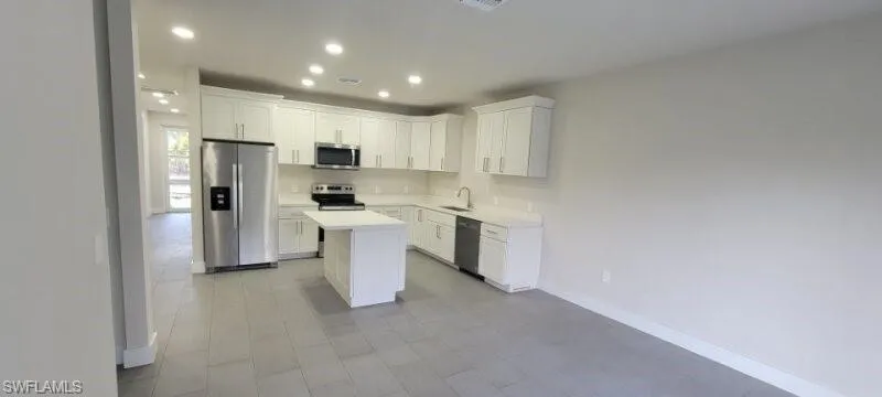 Kitchen featuring appliances with stainless steel finishes, light countertops, recessed lighting, baseboards, and a kitchen island