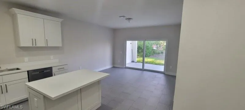 Kitchen with dishwasher, light countertops, baseboards, and a kitchen island