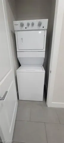 Laundry room with stacked washer / drying machine and light tile patterned flooring