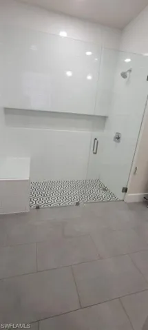 Full bath featuring a shower stall and tile patterned flooring