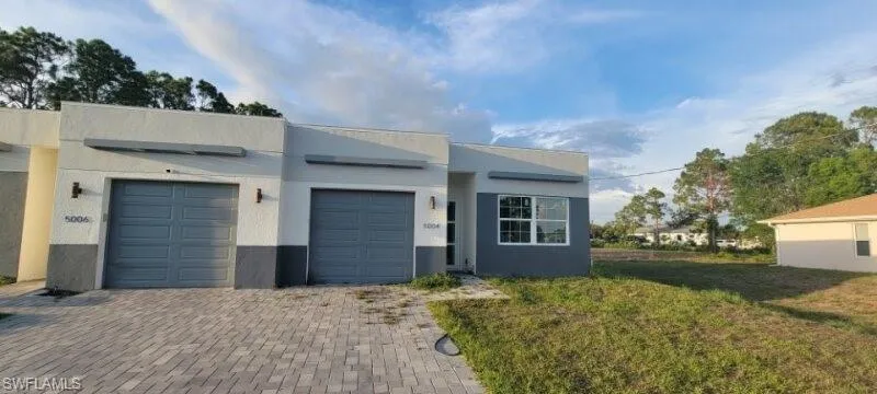 Contemporary house with an attached garage, decorative driveway, and stucco siding