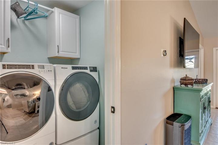 In home laundry room with upper cabinets and hanging shelf.