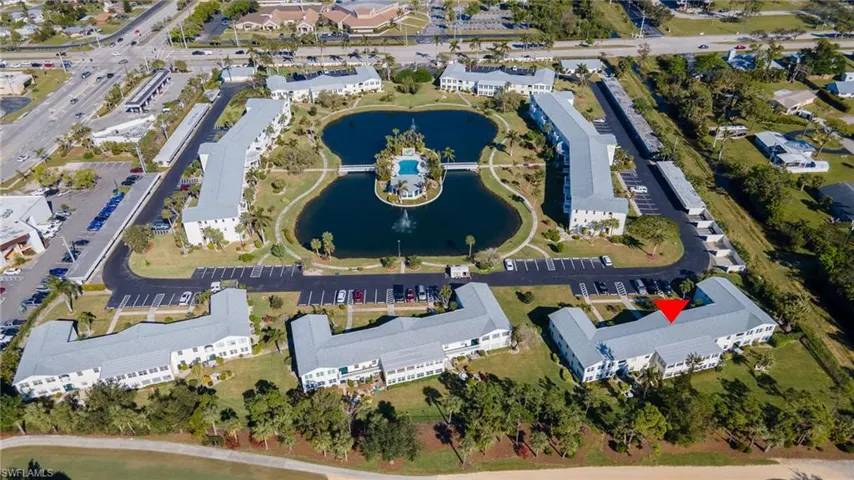 Aerial view of the community featuring multiple buildings, central water features, a community pool, and surrounding landscaping