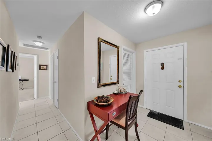 Entryway featuring a paneled white front door with brass hardware and a white louvered door