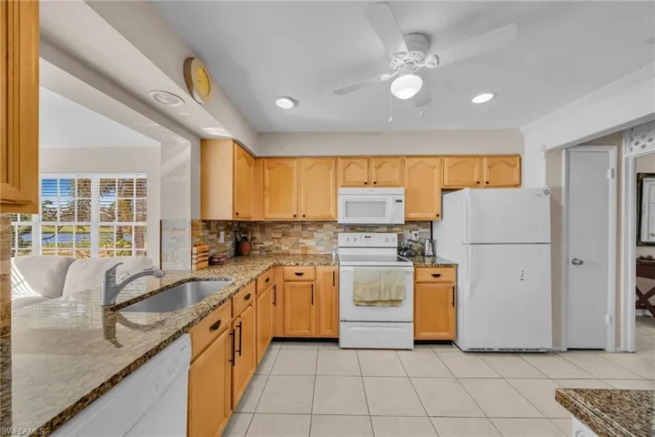 Well-appointed kitchen featuring light wood cabinetry, stone countertops, and tile flooring