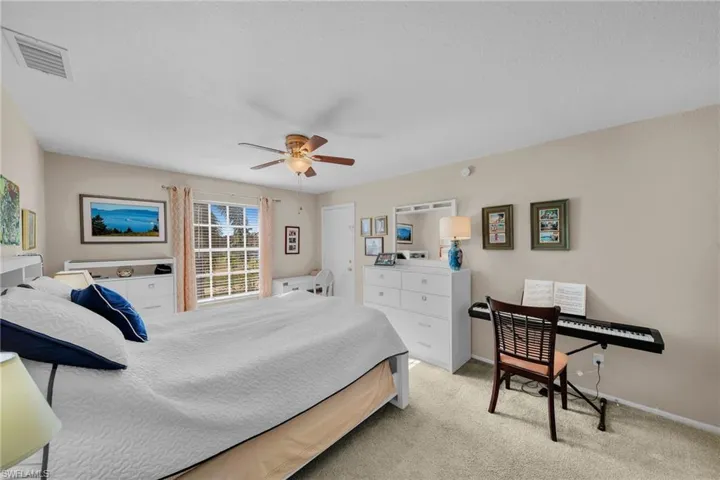 Spacious room featuring neutral-toned walls, light-colored carpeting, a multi-pane window with vertical blinds, and a ceiling fan with integrated lighting