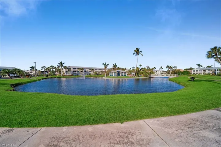 Expansive water feature with a fountain, surrounded by manicured lawns and mature palm trees
