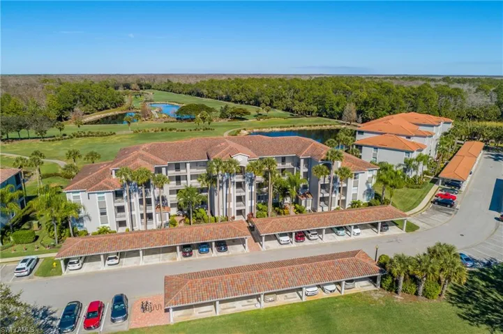 Drone / aerial view of the front of the building and a nearby body of water, preserve, and a local golf course