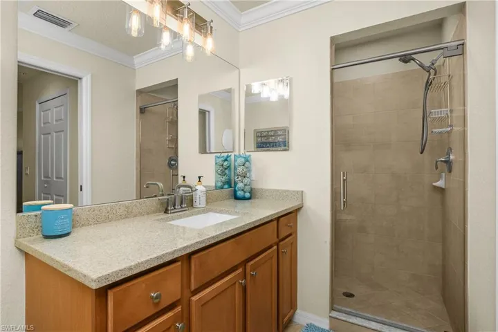 Primary Bathroom with ornamental molding, a stall shower, and vanity
