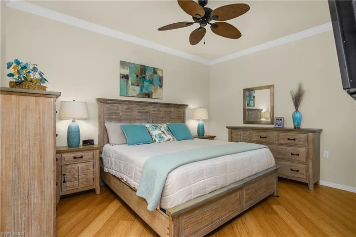 Primary Bedroom featuring crown molding, bamboo wood finished floors, and ceiling fan