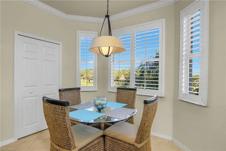 Dining area with light tile patterned tile flooring, healthy amount of natural light, plantation shutters, and crown molding
