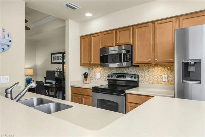 Kitchen with appliances with stainless steel finishes, an office area, and backsplash