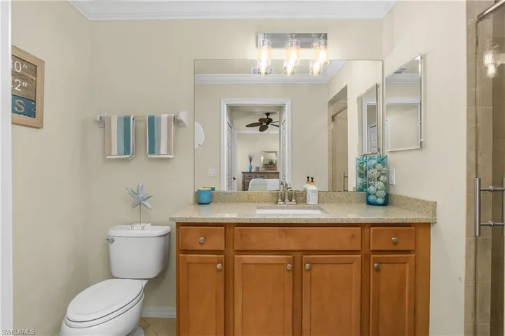 Full bath featuring a stall shower, vanity, ornamental molding, and ceiling fan