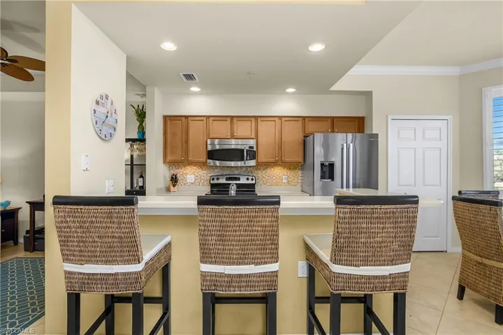 Kitchen featuring light countertops, stainless steel appliances, tasteful backsplash, and a kitchen breakfast bar