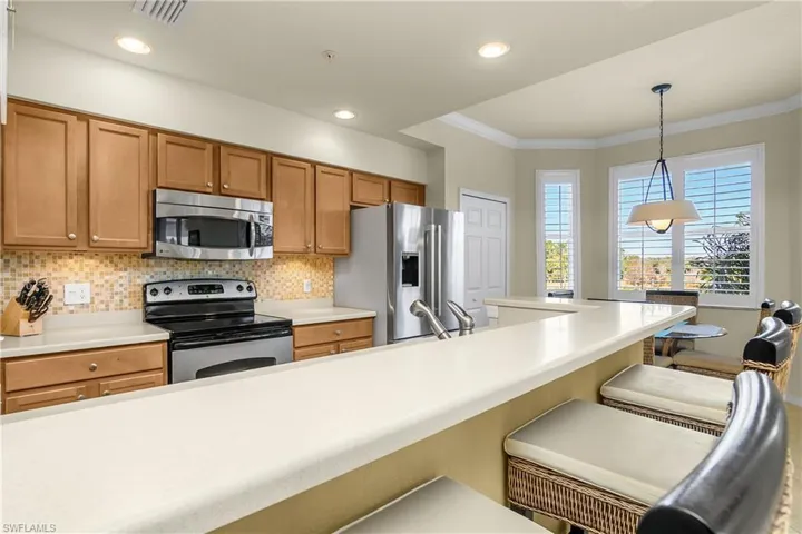 Kitchen featuring appliances with stainless steel finishes, a breakfast bar area, light countertops, and crown molding