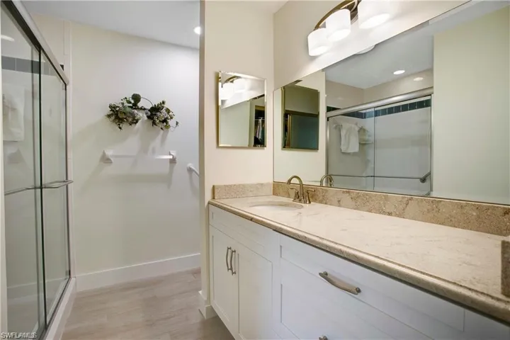 Primary Bath downstairs, white shaker cabinets, glass shower door, new lighting/plumbing fixtures.