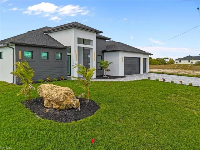 View of front of property with a front lawn, roof with shingles, decorative driveway, a garage, and stucco siding