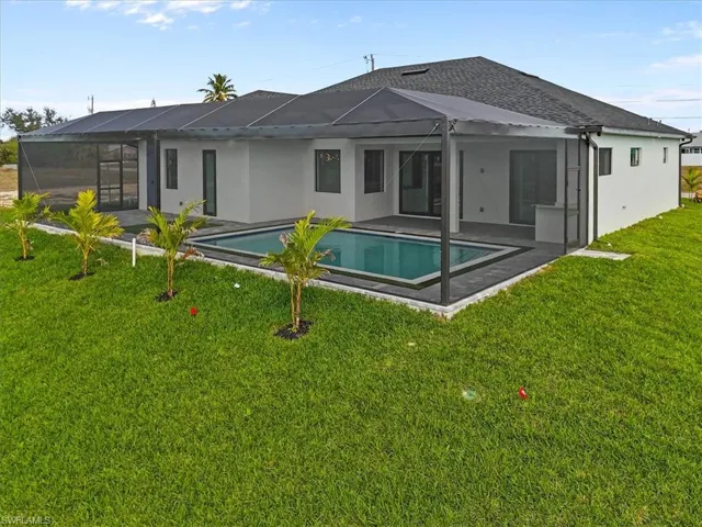Back of property with a sunroom, stucco siding, glass enclosure, and a lawn