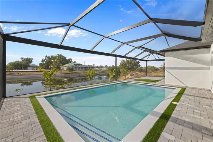 Outdoor pool with a sunroom, a lanai, a water view, and a patio area