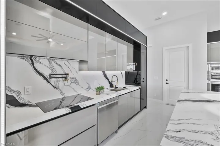 Kitchen featuring modern cabinets, light stone counters, recessed lighting, dishwasher, and light marble finish flooring