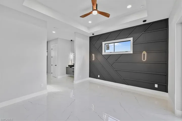 Unfurnished room with a tray ceiling, an accent wall, recessed lighting, a decorative wall, and ceiling fan