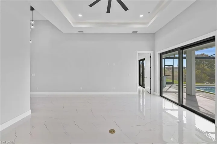 Empty room featuring light marble finish floors, a raised ceiling, recessed lighting, and a ceiling fan