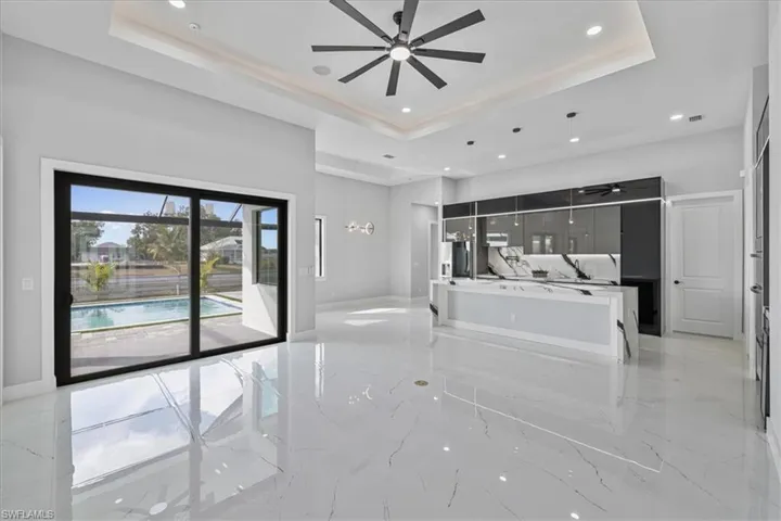 Unfurnished living room featuring a ceiling fan, light marble finish flooring, and recessed lighting