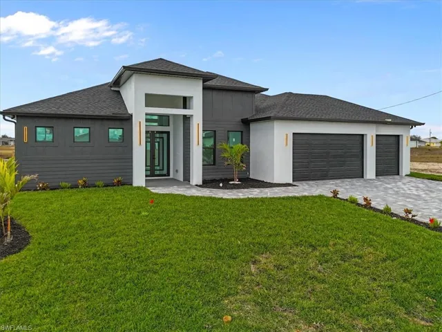 View of front of house with a shingled roof, a front lawn, and decorative driveway